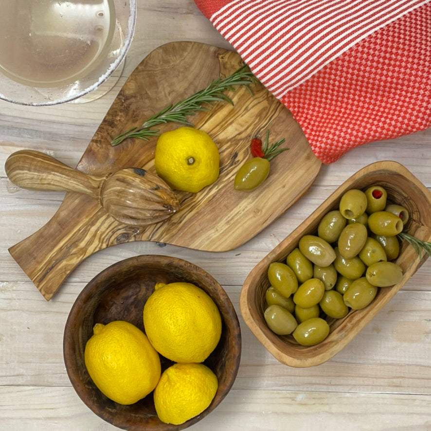 Olive wood bowls and cutting board on kitchen counter filled with olives and lemons, showcasing useful accessories as home accents.