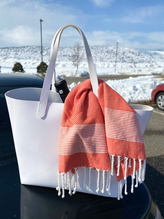 An orange hand towel draped over a white gym bag, showing the versatility of kitchen hand towels beyond the kitchen.
