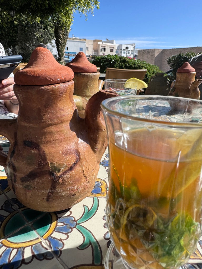 Clay teapots and mint-filled tea glasses on a rooftop table overlooking rooftops of a Tunisian city midday — moments that inspire curated decorative accents.