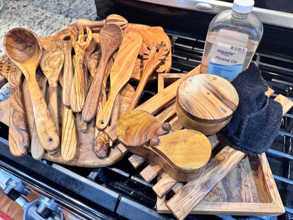 Olive wood kitchen utensils and cutting boards freshly oiled with mineral oil, showcasing how to care for your purchase.