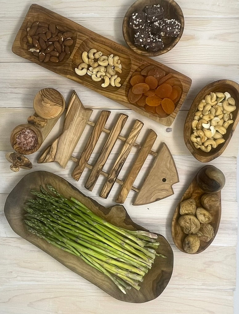 Olive wood cutting board with fresh asparagus and serving bowls filled with dried fruit and nuts, ideal housewarming gifts for any kitchen.