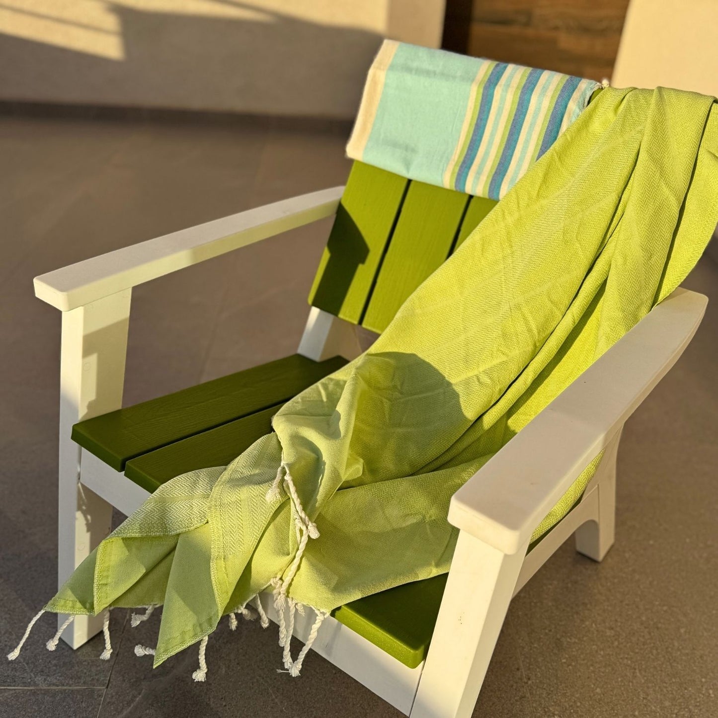 lime green fouta towel draped over outdoor chair in sunlight lightweight cotton towel for pool beach or patio