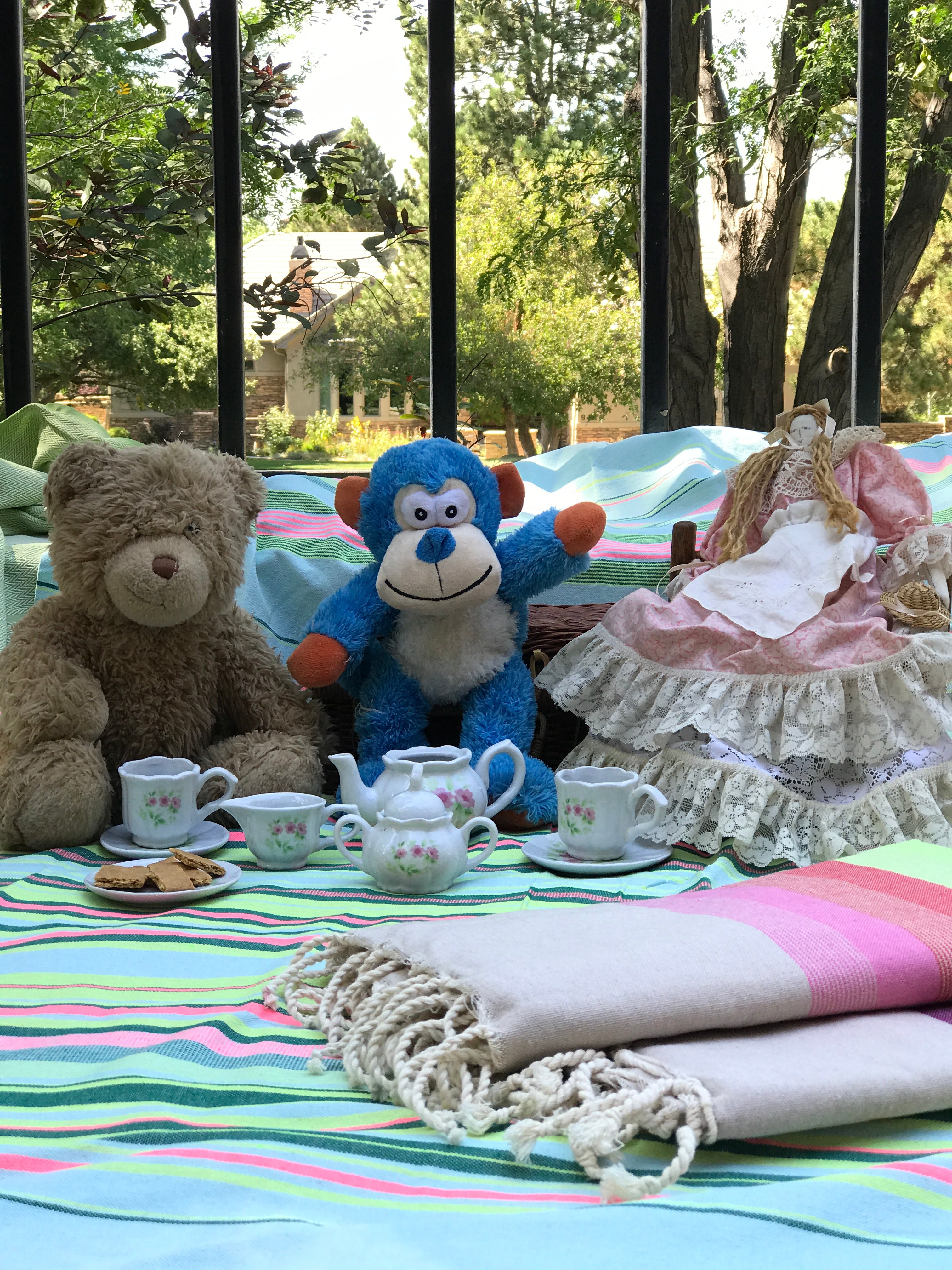 Large colorful striped fouta towel spread at a park tea party with stuffed animals, showing this unique home décor can add charm to outdoor fun.