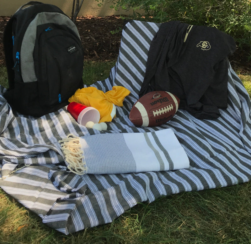 Oversized fouta towel used as a blanket on the grass during a football game, a versatile example of our woven cotton towels.