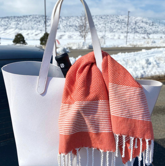 An orange hand towel draped over a white gym bag, showing the versatility of kitchen hand towels beyond the kitchen.