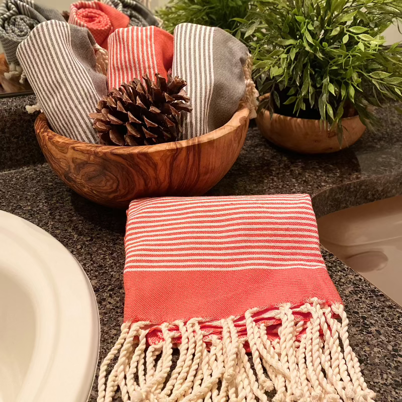 Fouta hand towels styled in olive wood bowls, a beautiful housewarming gift idea combining texture and function.