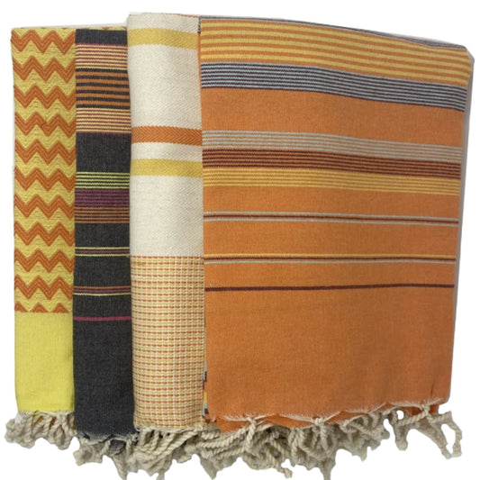 Nabeul Sun Tile Golden Hour fouta towel folded showing orange striped pattern and hand-finished tassels