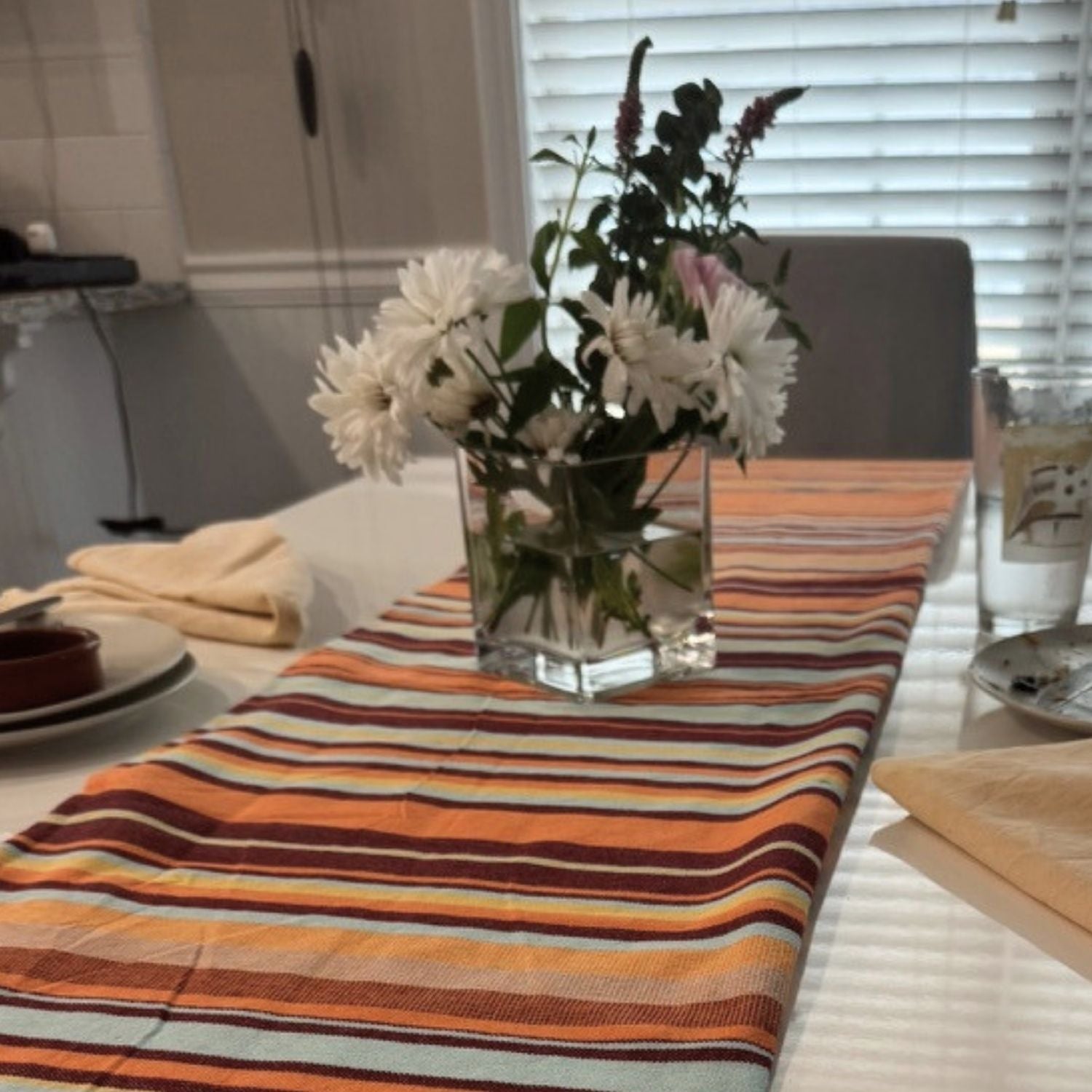 Nabeul Sun Tile Golden Hour fouta towel styled as table runner with flowers on dining table