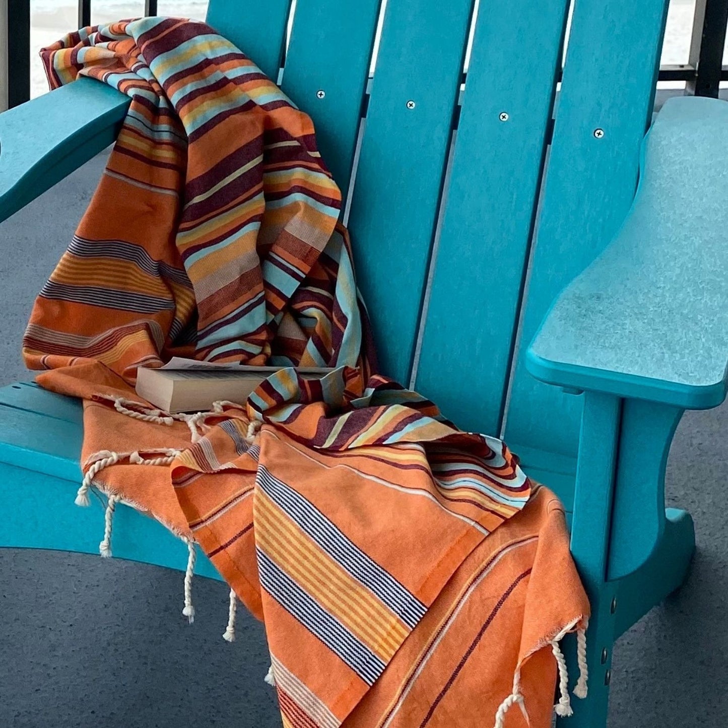 Nabeul Sun Tile Golden Hour fouta towel draped over turquoise chair highlighting texture and tassel detail