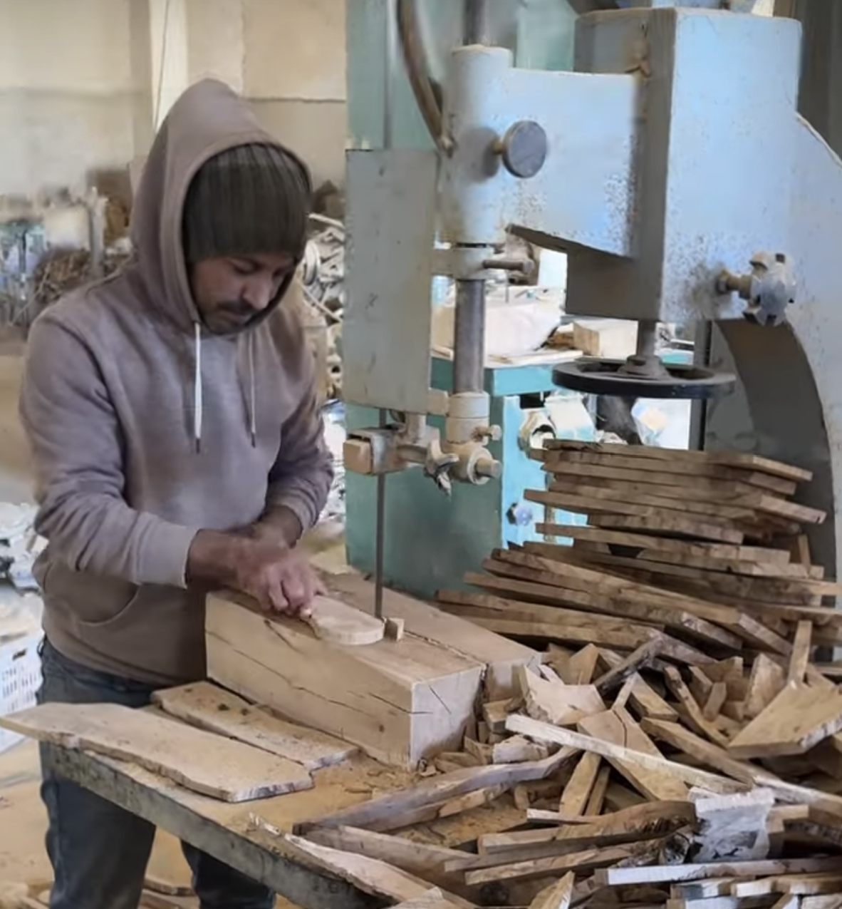 Karim using a jigsaw to follow a drawn spoon template on an olive wood slab — cutting each olive wood spoon with care and precision.